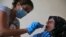 FILE - A member of the International Red Cross takes a saliva sample from a woman whose sister went missing in 1976 during the Lebanese civil war, at her home, in a southern suburb of Beirut, Lebanon, July 11, 2016.