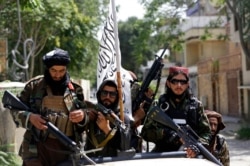 FILE - Taliban fighters display their flag on patrol in Kabul, Afghanistan, Aug. 19, 2021.