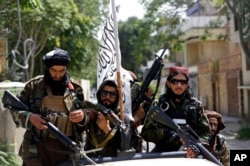 FILE - Taliban fighters display their flag on patrol in Kabul, Afghanistan, Aug. 19, 2021.