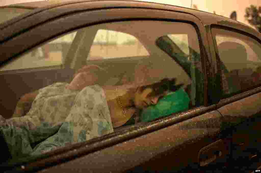 People sleep in their car on the beach as wildfire rages in Pefki village on Evia (Euboea) island, second largest Greek island, Aug. 8, 2021.