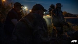 FILE - Members of a militia patrol the U.S.-Mexico border in Sunland Park, New Mexico, March 20, 2019.