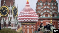 People take photos in front of the Kremlin's Spasskaya tower and St. Basil's cathedral in downtown Moscow on Nov. 10, 2023.