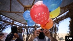 Pendukung Palestina terlihat menyiapkan balon yang mudah menyulut api dalam sebuah aksi protes terhadap militer Israel yang dilakukan di perbatasan Gaza pada 15 Juni 2021. (Foto: AFP/Mahmud Hams)