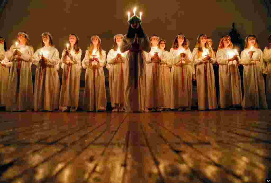 Young women sing carols as they hold candles to celebrate St. Lucia&#39;s Day in the Evangelical Lutheran Church of Saint Katarina in St. Petersburg, Russia.