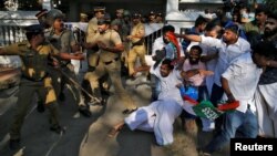 A police officer wields his stick against the members of Kerala Students Union (KSU), the student wing of India's main opposition Congress party, outside a police station during a protest in Kochi, India, Jan. 3, 2019. 