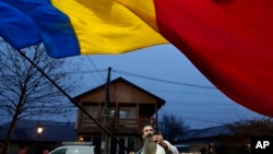 A man waves the Romanian flag outside a closed voting station after Romania's Constitutional Court annulled the first round of presidential elections, in Mogosoaia on Dec. 8, 2024. The EU said on Dec. 17 it was investigating video-sharing platform TikTok regarding the election.