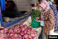 FILE - A woman counts Moroccan currency at a vegetable market in Casablanca, Morocco, June 29, 2017.