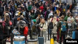 Travelers navigate through a security checkpoint at Hartsfield-Jackson Atlanta International Airport ahead of the Thanksgiving holiday in Atlanta, Georgia, Nov. 22, 2022. 