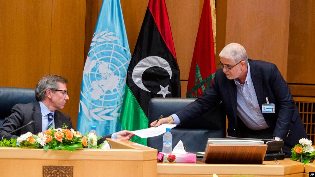 Wakil Khusus PBB untuk Libya, Bernardino Leon (kiri), menerima dokumen dari Mustafa Abushagur, perwakilan pemerintahan Libya yang diakui, dalam pertemuan di Skhirate, Maroko (2/7).