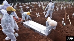 Grave diggers bury the coffin of a man who died from from COVID-19 at a cemetary in Bekasi, as Indonesia passed the grim milestone of over 100,000 COVID-19 deaths.