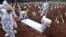 Grave diggers bury the coffin of a man who died from from COVID-19 at a cemetary in Bekasi, as Indonesia passed the grim milestone of over 100,000 COVID-19 deaths.