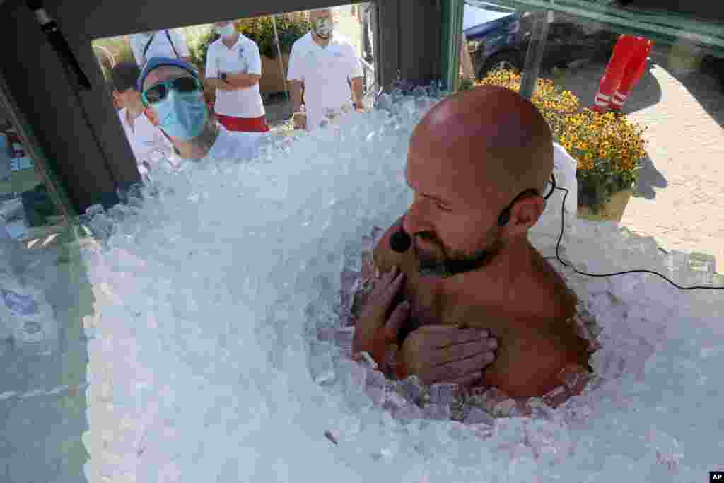 Austrian ice swimmer Josef Koeberl is standing in a glass cabin filled with ice to break the world record for a human to stay side an ice box in Melk, Sept. 5, 2020.