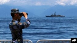 中共新华社发布的照片：中国军队围绕台湾岛举行的军演期间，一名中国海军士兵从军舰上观察台湾海军兰阳号飞弹巡防舰。（2022年8月5日）