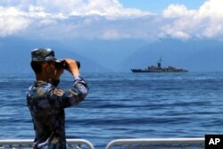 中共新華社發布的照片：中國軍隊圍繞台灣島舉行的軍演期間，一名中國海軍士兵從軍艦上觀察台灣海軍蘭陽號飛彈巡防艦。（2022年8月5日）
