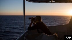 A member of "SOS Mediterranee", an European association dedicated to search and rescue, uses binoculars during a search operation on the Mediterranean sea, 30 nautical miles from the Libyan coast, July 31, 2017. 