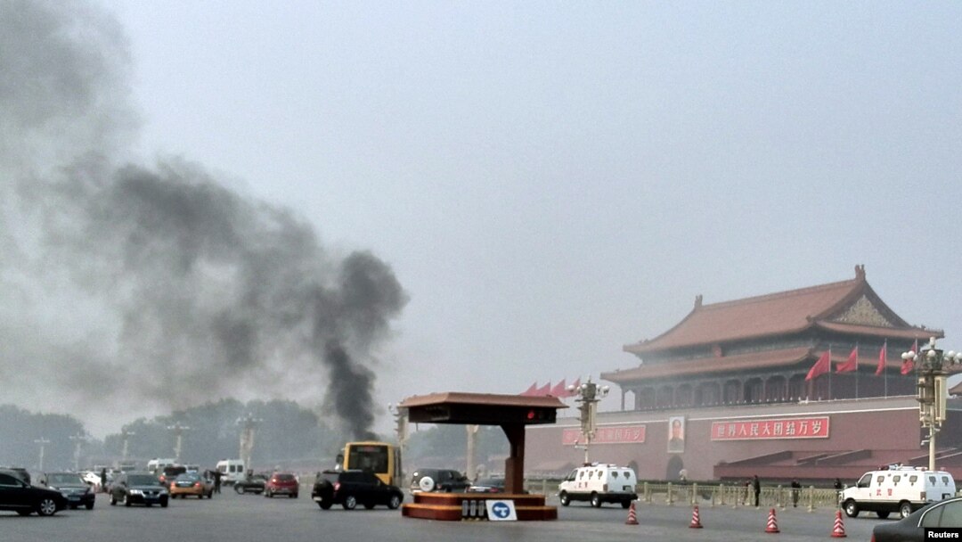 Asap mengepul tidak jauh dari foto besar Mao Zedong di Lapangan Tiananmen akibat sebuah jip menabrak kerumunan dan terbakar hari Senin (28/10). 