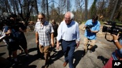 FILE - Democratic presidential candidate Sen. Bernie Sanders, I-Vermont (R) talks with area resident Michael Ranney as he tours a mobile home park that was destroyed by last year's wildfire in Paradise, Calif., Aug. 22, 2019.