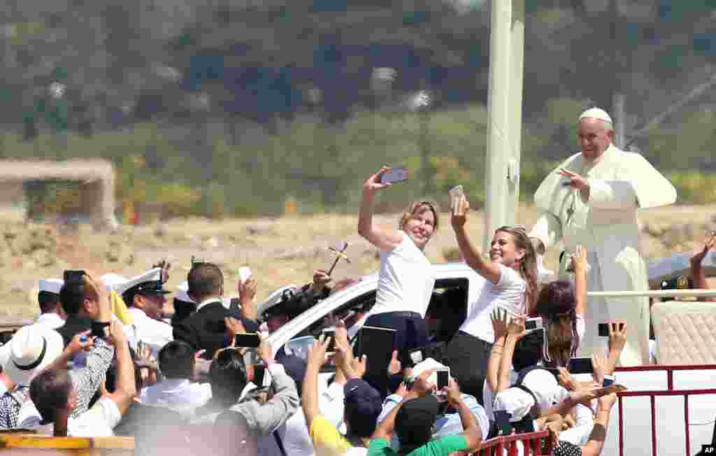 Pope Francis waves to the crowd as he rides in the popemobile through Samanes Park, where he will celebrate Mass, in Guayaquil, Ecuador.