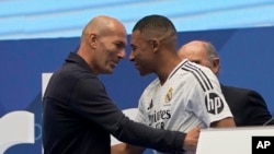 Kylian Mbappé, de Francia, abraza al exjugador francés Zinedine Zidane,, mientras es presentado a los fanáticos como nuevo jugador del Real Madrid en el estadio Santiago Bernabéu en Madrid, el martes 16 de julio de 2024.