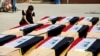 FILE - A man sits next to coffins holding the remains of Yazidis killed in Islamic State attacks in 2014, after they were exhumed from a mass grave in Mosul, Iraq, June 20, 2023. Germany said on April 10, 2024, it arrested an Iraqi couple accused of genocide against the Yazidis.