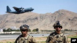 In this image provided by the Defense Department, two paratroopers assigned to the 1st Brigade Combat Team, 82nd Airborne Division, conduct security while a C-130 Hercules takes off during an evacuation operation in Kabul, Afghanistan, Aug. 25, 2021.