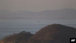 A North Korean ship passes between the North Korean mainland, background, and the South Korean island of Yeonpyeong, foreground, 26 Nov 2010