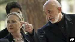 ລັດຖະມົນຕີການຕ່າງປະເທດສະຫະລັດທ່ານນາງ Hillary Clinton (ຊ້າຍ) ແລະປະທານາທິບໍດີ Hamid Karzai ແຫ່ງ ອັຟການິສຖານ ພວມພາກັນຍ່າງໄປກອງປະຊຸມຖະແຫຼງຂ່າວ ທີ່ທຳນຽບປະທານາທິບໍດີ ໃນນະຄອນຫຼວງກາບູລ (7 ກໍລະກົດ 2012)