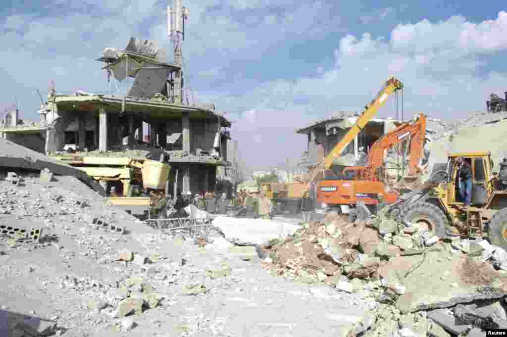 9일 시리아 알-카파트 시 차량 폭탄 테러 현장에서 포크레인이 건물 잔해를 청소하고 있다.