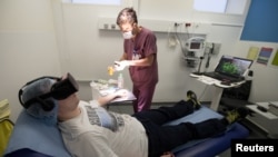 A nurse treats a patient wearing the 3-D therapeutic virtual reality headset developed by the Healthy Mind startup, at the emergency services department of the Saint-Joseph Hospital in Paris, June 7, 2018. 