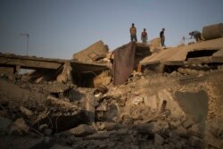 Anggota sebuah keluarga berdiri di atap rumah mereka yang rusak di sisi barat Mosul, Irak, 2017. (Foto: AP)