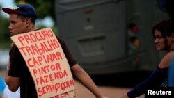 Un migrante venezolano porta una pancarta para solicitar un trabajo cerca de un campamento improvisado en la plaza Simón Bolívar en Boa Vista, Brasil, 3 de mayo de 2018.