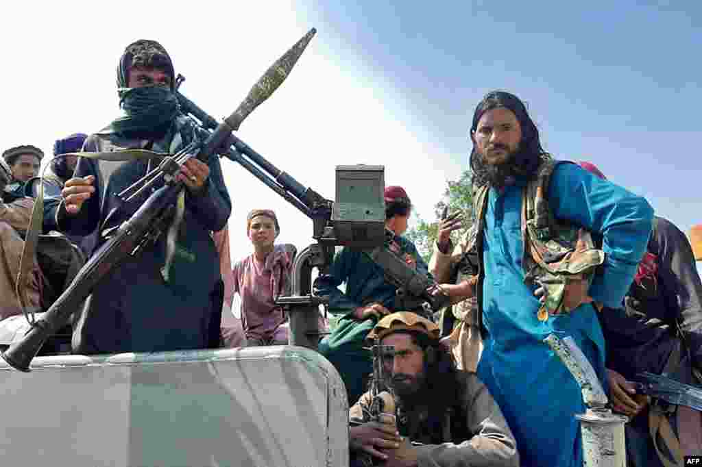 Taliban fighters sit over a vehicle on a street in Laghman province, Afghanistan.