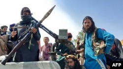 FILE - Taliban fighters sit over a vehicle on a street in Laghman province on Aug. 15, 2021. 