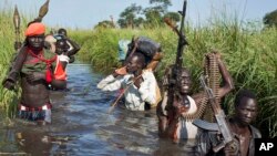 Rebel soldiers patrol and protect civilians from the Nuer ethnic group as the civilians walk through flooded areas to reach a makeshift camp for the displaced situated in the United Nations Mission in South Sudan (UNMISS) base in the town of Bentiu, South Sudan, Sept. 20, 2014.