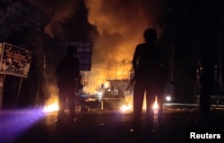 Pasukan keamanan siaga sementara sebuah gedung terbakar dalam aksi protes rusuh di Jayapura, Papua, Kamis malam (29/8). (Foto: Antara/Reuters)