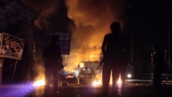 Pasukan keamanan siaga sementara sebuah gedung terbakar dalam aksi protes rusuh di Jayapura, Papua (29/8) (Foto: Antara/Reuters). Pemerintah memutus akses internet selama beberapa hari di Papua pasca demonstrasi rusuh.
