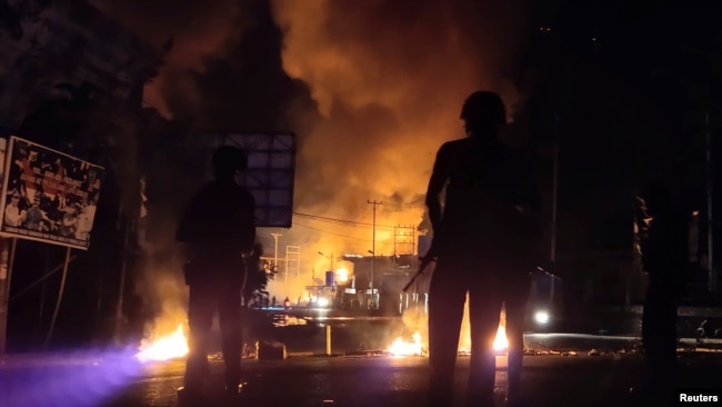 Pasukan keamanan siaga sementara sebuah gedung terbakar dalam aksi protes rusuh di Jayapura, Papua (29/8) (Foto: Antara/Reuters). Pemerintah memutus akses internet selama beberapa hari di Papua pasca demonstrasi rusuh.