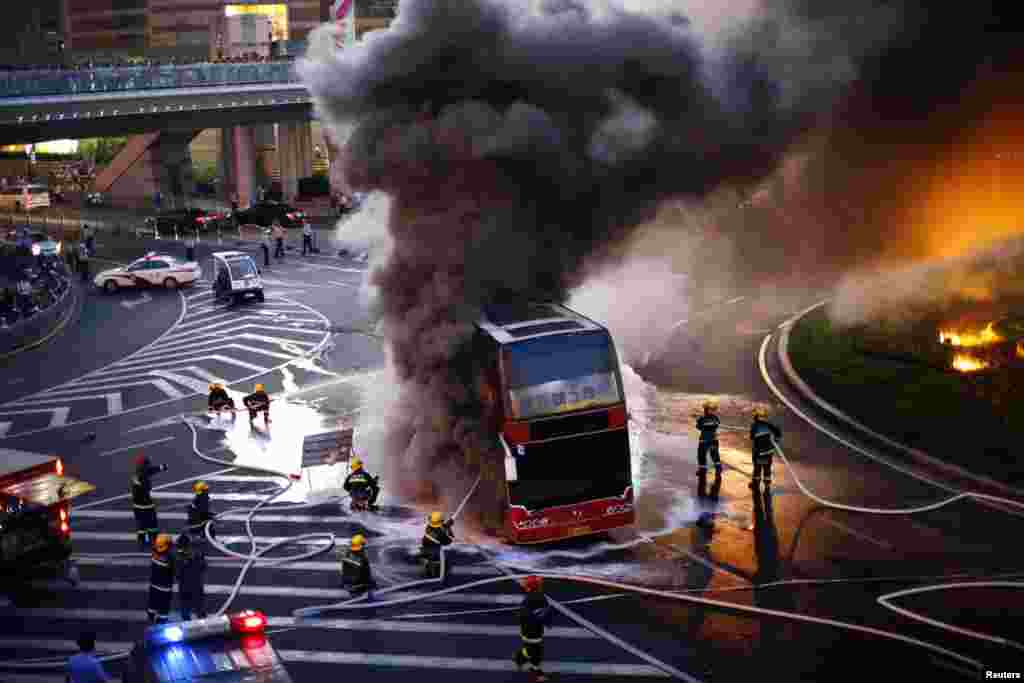 Para petugas pemadam kebakaran menyemprotkan air untuk memadamkan api pada bus pariwisata yang terbakar di depan Menara Oriental Pearl di distrik Pudong, Shanghai, China.