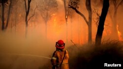 A New South Wales (NSW) Rural Fire Service firefighter sprays water on a bushfire in the suburb known as Salt Ash, located north of Newcastle in Australia, Nov. 23, 2018.