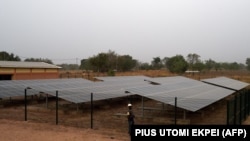 Un ingénieur se tient à côté d'une clôture protégeant un panneau solaire installé dans le village de Takpapieni dans la province d'Oti, au nord du Togo, le 14 février 2020. (Photo AFP/ PIUS UTOMI EKPEI)