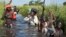 Rebel soldiers patrol and protect civilians from the Nuer ethnic group as the civilians walk through flooded areas to reach a makeshift camp for the displaced situated in the United Nations Mission in South Sudan (UNMISS) base in the town of Bentiu, South Sudan, Sept. 20, 2014.
