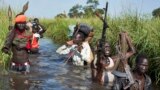 Rebel soldiers patrol and protect civilians from the Nuer ethnic group as the civilians walk through flooded areas to reach a camp for the displaced in the town of Bentiu, South Sudan. More than 2 million South Sudanese have been displaced by 18 months of fighting.