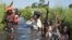 Rebel soldiers patrol and protect civilians from the Nuer ethnic group as the civilians walk through flooded areas to reach a camp for the displaced in the town of Bentiu, South Sudan. More than 2 million South Sudanese have been displaced by 18 months of fighting.