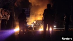 Pasukan keamanan siaga sementara sebuah gedung terbakar dalam aksi protes rusuh di Jayapura, Papua, Kamis malam (29/8). (Foto: Antara/Reuters)