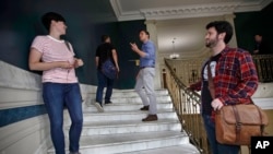 Zak Ringelstein, center, a Democratic candidate for U.S. Senate in Maine, talks with a passerby while climbing the stairs inside City Hall to attend a meeting of the Southern Maine Democratic Socialists of America in Portland, Maine, Monday, July 16, 2018