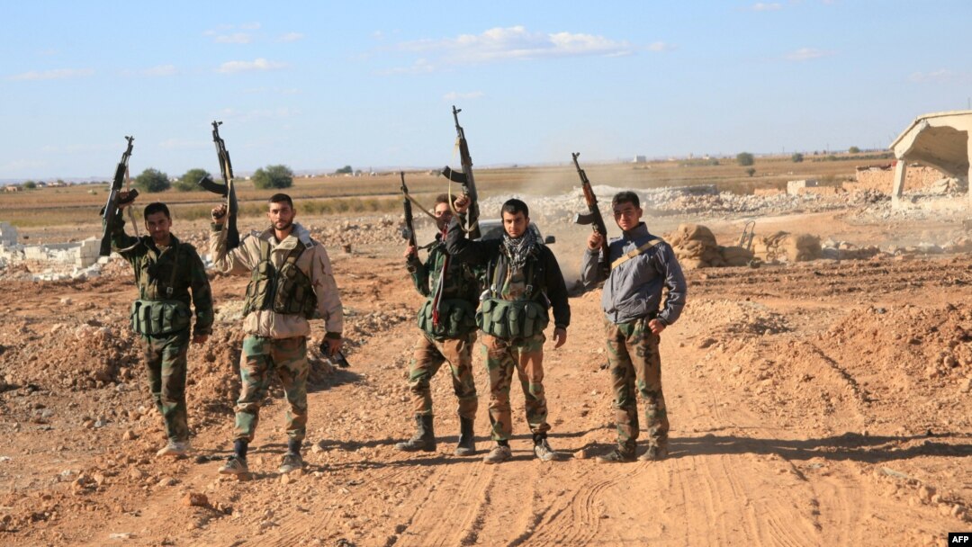 A group of Syrian pro-government forces raise their guns in celebration on the outskirts of Kweyris near the Kweyris military air base, east of the Syrian province of Aleppo, Nov. 10, 2015. 