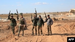 A group of Syrian pro-government forces raise their guns in celebration on the outskirts of Kweyris near the Kweyris military air base, east of the Syrian province of Aleppo, Nov. 10, 2015. 