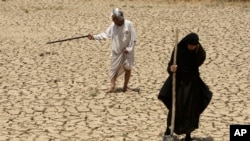 Adilla Finchaan, 50, and her husband, Ashore Mohammed, 60 walk their dried-up farmland in Iraq in this 2009 photograph. The Tigris-Euphrates region suffered consecutive years of drought.
