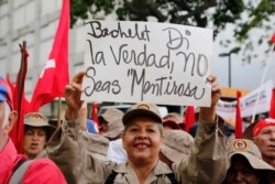 FILE - A member of the Bolivarian militia holds up a sign that reads in Spanish: "Bachelet tell the truth" during a protest against Michelle Bachelet, the U.N. high commissioner for human rights, in Caracas, Venezuela, July 13, 2019.