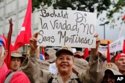 FILE - A member of the Bolivarian militia holds up a sign that reads in Spanish: "Bachelet tell the truth" during a protest against Michelle Bachelet, the U.N. high commissioner for human rights, in Caracas, Venezuela, July 13, 2019.